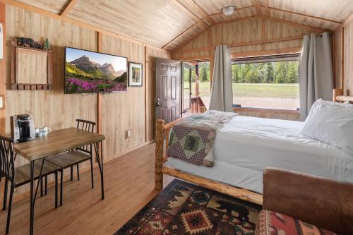 a bedroom with a bed and a table and a window at Sky Eco - Glacier General Store and Cabins in Coram