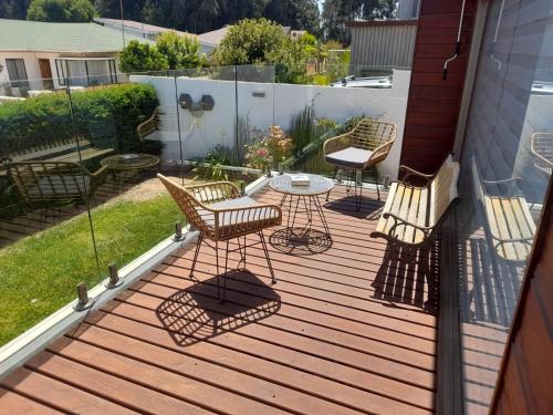 a deck with three chairs and a table on it at CASA MIRASOL in Algarrobo