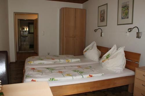 um quarto com duas camas com lençóis brancos e flores em Gästehaus Braunegger em Lamprechtshausen