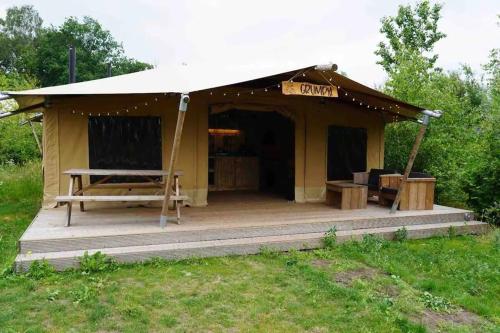 a tent with a table and a bench in a field at Luxe en romantische overnachting 4 personen Grumpy in Behelp