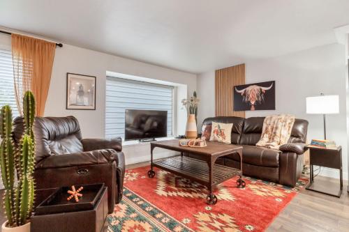 a living room with a leather couch and a table at Backyard BBQ Retreat: Central 3bd - Prime Location in Arvada