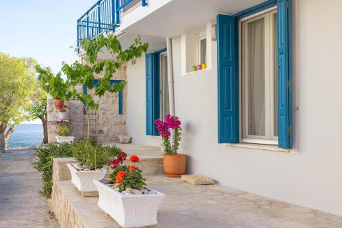 a row of flower pots on a building with blue doors at Pythagoreio Blue Street Apartment with Terrace in Pythagoreio