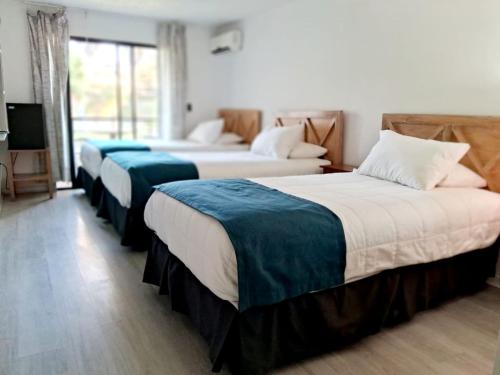 una camera d'albergo con tre letti e una televisione di Hotel Palmas de La Serena a La Serena