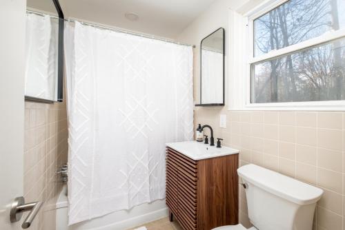 uma casa de banho com uma cortina de chuveiro branca e um WC. em Downtown Brevard, Franklin Park & College - Updated 3bd 2ba home, Pets ok em Brevard
