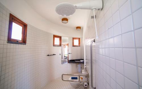 a white tiled bathroom with a toilet and a sink at VentoVinte Beach Club in Flecheiras