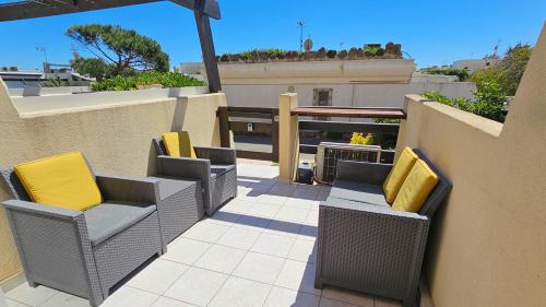un patio avec des chaises en osier et des coussins jaunes sur un balcon dans l'établissement CapSexy Port Nature Garden Naturist Village, au Cap d'Agde