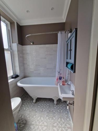 a bathroom with a tub and a toilet and a sink at Garden Beach Apartment, Hunstanton Norfolk in Hunstanton