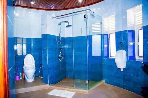 La salle de bains est pourvue de carrelage bleu, de toilettes et d'une douche. dans l'établissement NETLUNA VILLA HOTEL, à Kigali