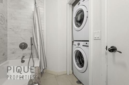 a bathroom with a washing machine and a washer at Mountain Haven Retreat, Pool & Hot Tub, UG Parking, Fitness Centre, WiFi! in Canmore