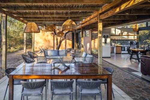 ein Esszimmer mit einem großen Holztisch und Stühlen in der Unterkunft Rixile Kruger Lodge in Skukuza