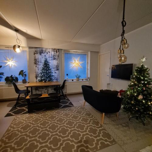 a living room with a christmas tree and two windows at Lakeland Apartments in Rovaniemi