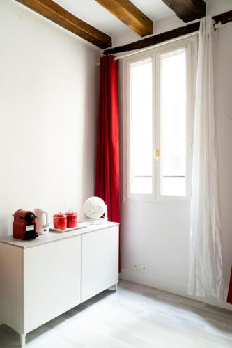 une cuisine avec des placards blancs et une grande fenêtre dans l'établissement Le 64 Rue Chapon, à Paris