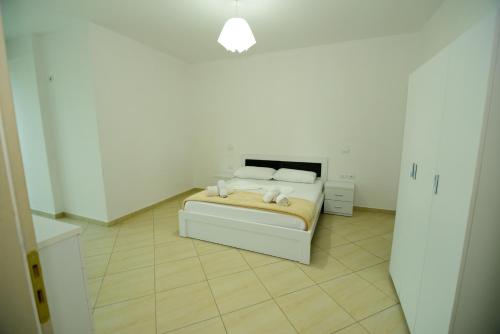a white bedroom with a bed with two pillows at Harris&Arvien Apartment's in Vlorë