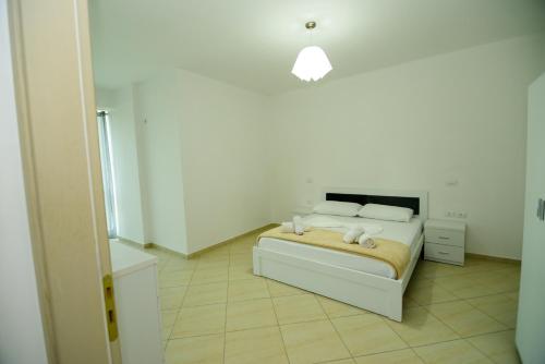 a white bedroom with a bed with two pillows at Harris&Arvien Apartment's in Vlorë