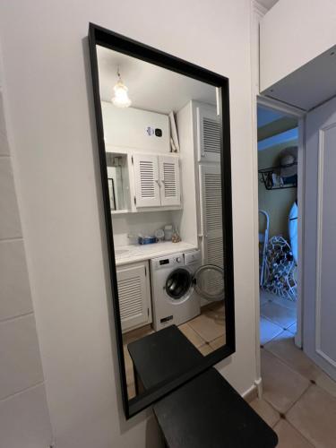 un miroir reflétant une cuisine avec une machine à laver dans l'établissement Belle vue Golfe de St Tropez Marines de Cogolin La Galiote, à Cogolin