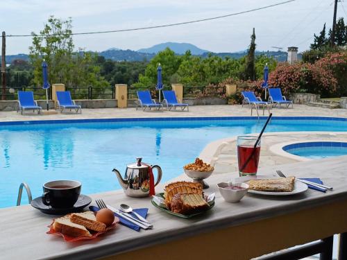 a table with breakfast food on it next to a pool at Penelope Apartment Hotel in Dassia