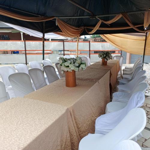 eine Reihe von Tischen und weißen Stühlen unter einem Zelt in der Unterkunft Hotel De Pisces in Uyo