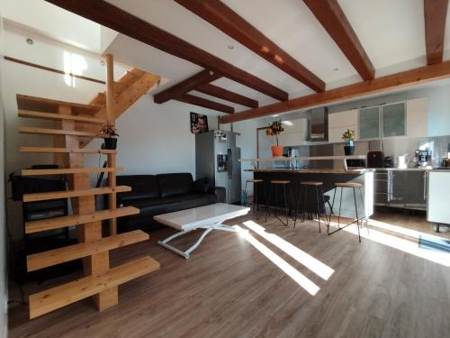 uma sala de estar com um sofá preto e uma cozinha em Housse Chaleureuse et Confortable em Osny