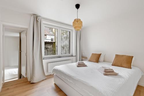 a white bedroom with a bed and a window at Studio Petite Plage in Ostend