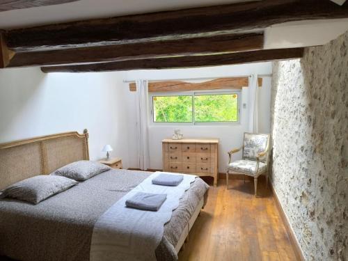 a bedroom with a bed and a chair and a window at Grande suite en duplex avec 2 chambres, terrasse dans corps de ferme in Villiers-sous-Grez