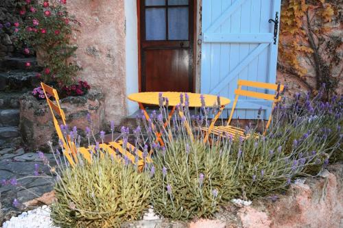a table and chairs in front of a house with flowers at La petite maison dans les nuages in Tourtour