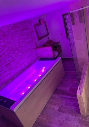 Cette chambre violette dispose d'une baignoire avec des lumières violettes. dans l'établissement La petite maison dans les nuages, à Tourtour