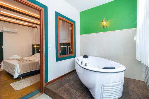 a bathroom with a tub and a bedroom with a bed at Pousada Arvoredo in Pirenópolis
