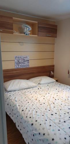 une chambre avec un lit avec une tête de lit en bois dans l'établissement Mobile-home 2 chambres, à Onzain