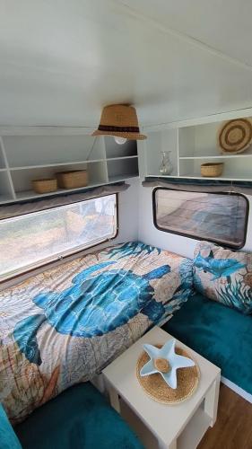 a small bedroom with a bed and a table at Gerestylde vintage caravan "Zee" met luxe badkamer bij "de Kapitein" in 't Horntje