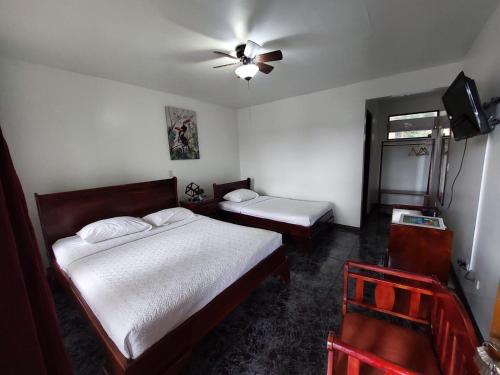1 dormitorio con 2 camas y ventilador de techo en Brillasol Airport Hotel, en Alajuela