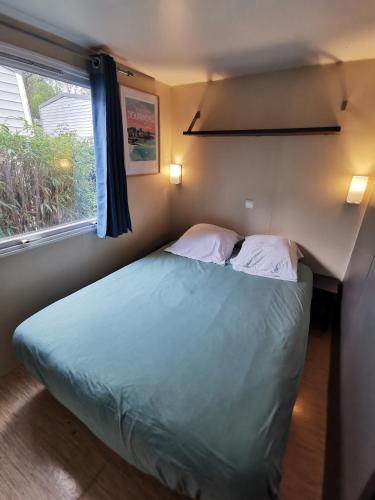 - une chambre avec un lit avec deux oreillers et une fenêtre dans l'établissement Mobil-home dans le calme du Domaine de Lanniron R24, à Quimper