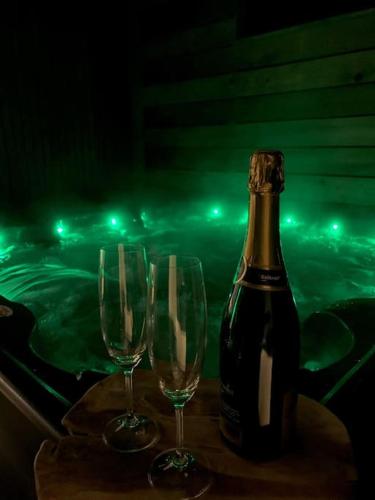 - une bouteille de champagne et 2 verres à vin sur une table dans l'établissement Lodge Cosy - Sauna & Jacuzzi., à Saint-Coulitz