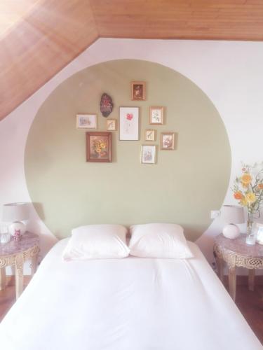 - une chambre dotée d'un lit blanc avec des photos sur le mur dans l'établissement Fleur, à Salles-Curan