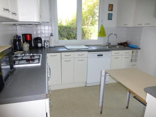 - une cuisine avec des placards blancs, un évier et une table dans l'établissement MAISON proche PLAGE TERRAIN DE TENNIS Le Pouliguen, au Pouliguen