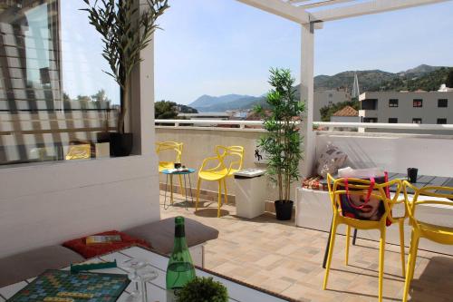 einen Balkon mit gelben Stühlen und einem Tisch auf dem Dach in der Unterkunft Hostel Petra Marina in Dubrovnik