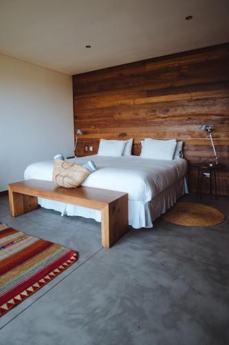 a bedroom with a large bed and a wooden wall at Hotel Alaia in Pichilemu