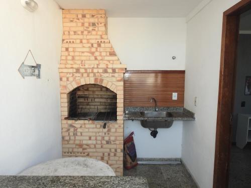 a brick fireplace in a kitchen with a sink at Cobertura Canto da Sereia in Arraial do Cabo