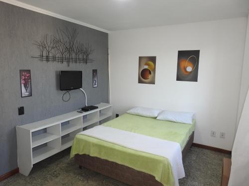 a bedroom with a bed and a desk with a tv at Cobertura Canto da Sereia in Arraial do Cabo