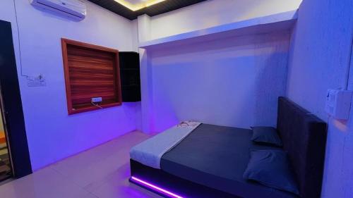 PALLAV GUEST HOUSE في اوجاين: غرفة نوم مع سرير مع أضواء أرجوانية عليه