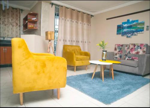 a living room with two yellow chairs and a table at The cape vills in Kampala
