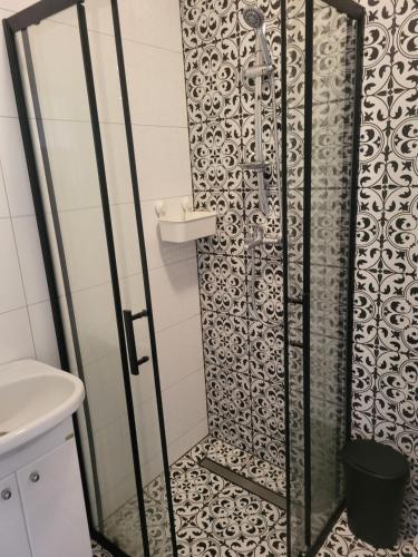 La salle de bains est pourvue d'une douche et de carrelage noir et blanc. dans l'établissement APARTAMENT PRZY WYSPIE, à Darłowo