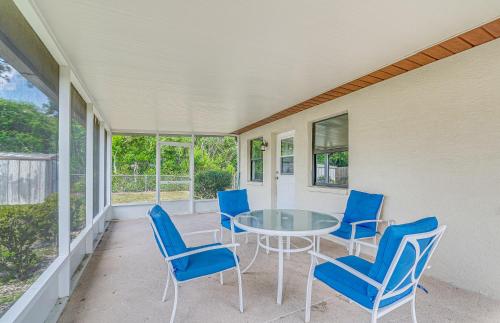 a porch with a glass table and blue chairs at 13 Mi to Hudson Beach Spring Hill Home with Lanai in Spring Hill