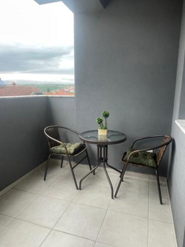 a table and two chairs in a room with a window at Bela in Kumanovo