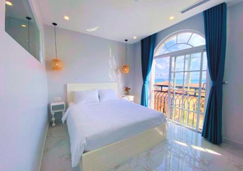 a bedroom with a bed and a large window at Moonlight Hotel Phu Quoc in Phu Quoc