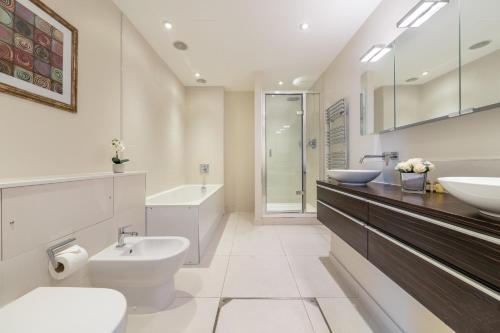 uma casa de banho branca com 2 lavatórios e um WC em Mayfair - Exclusive 4 Bedroom Apartment em Londres