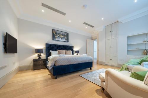 um quarto com uma cama azul e um sofá em Mayfair - Exclusive 4 Bedroom Apartment em Londres