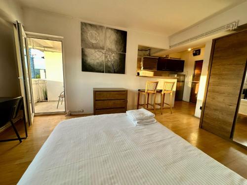 a bedroom with a large white bed and a kitchen at Cozy studio in the center of Cluj in Cluj-Napoca
