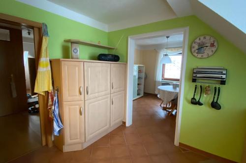 a kitchen with green walls and a clock on the wall at Wohnung im Grünen, Haus Cara, 120m², 4 Zi, Kü, Bad in Schkeuditz