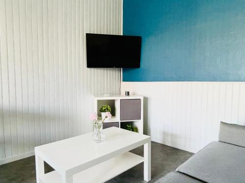 a living room with a white table and a tv at T2 au rez de chaussée dans propriété privée, au bord de l'eau à 15 minutes de Nancy in Toul