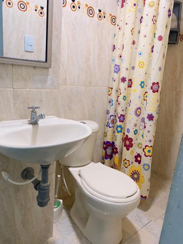 a bathroom with a sink and a toilet and a shower curtain at Cabañas Ypaos in Coveñas